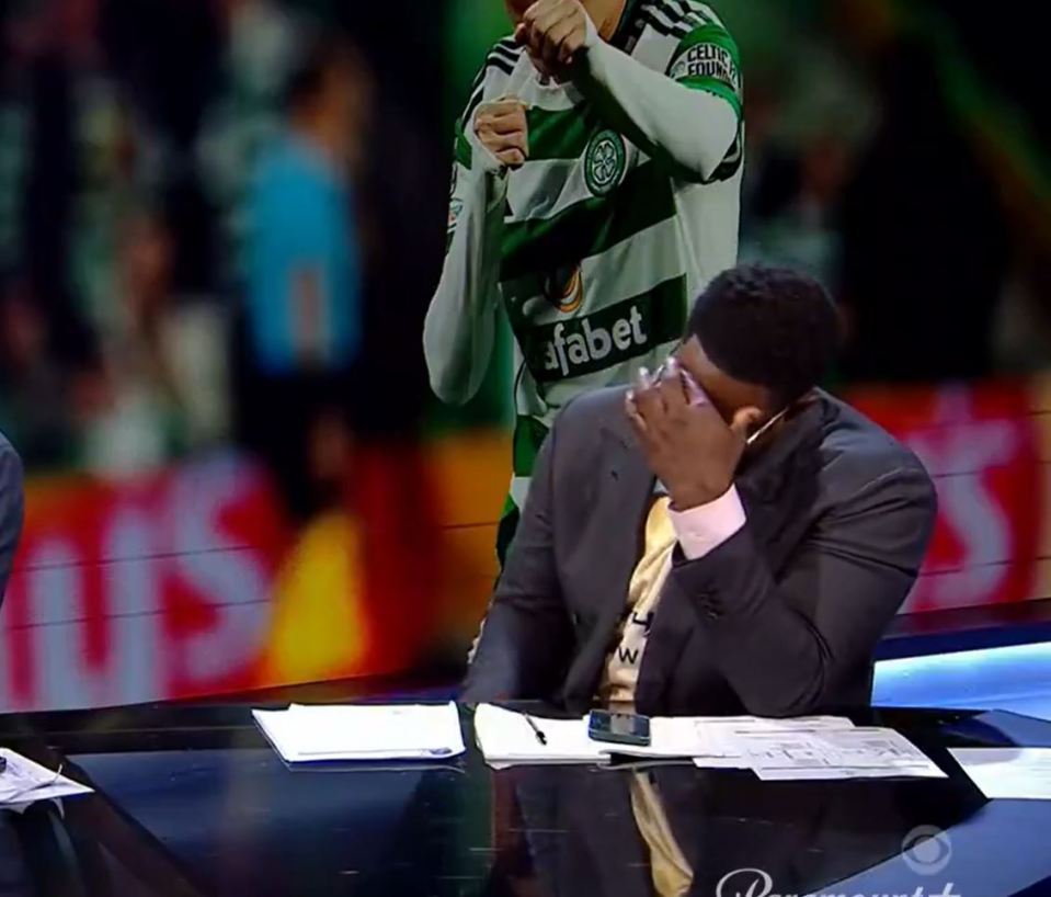 a man in a suit is covering his face in front of a celtic player wearing an dafabet jersey