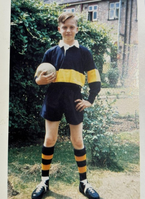 a young boy in a yellow and black jersey holds a soccer ball