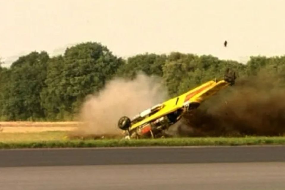 a yellow race car is crashing on its side on a race track .