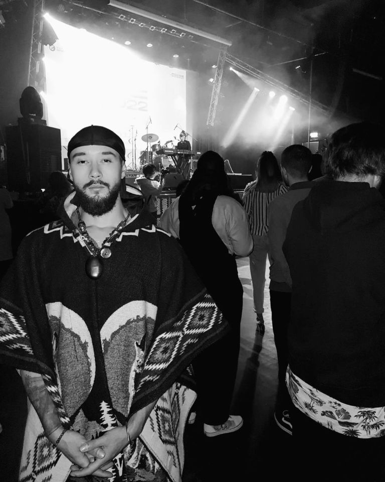 a man in a poncho stands in front of a stage