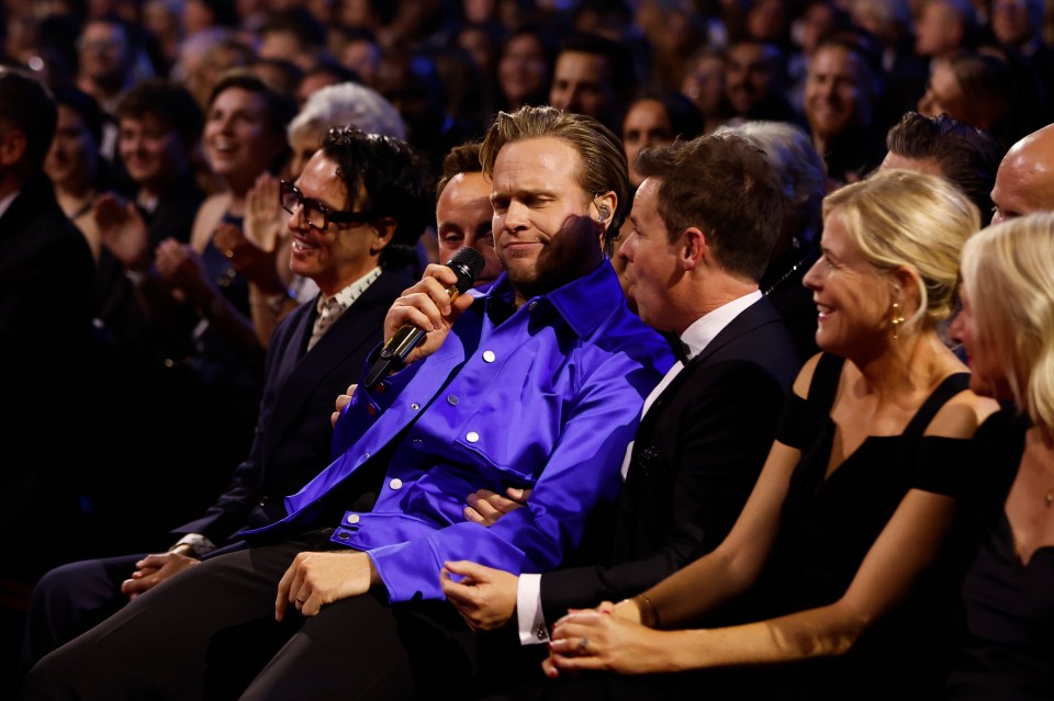 a man in a blue shirt is talking into a microphone