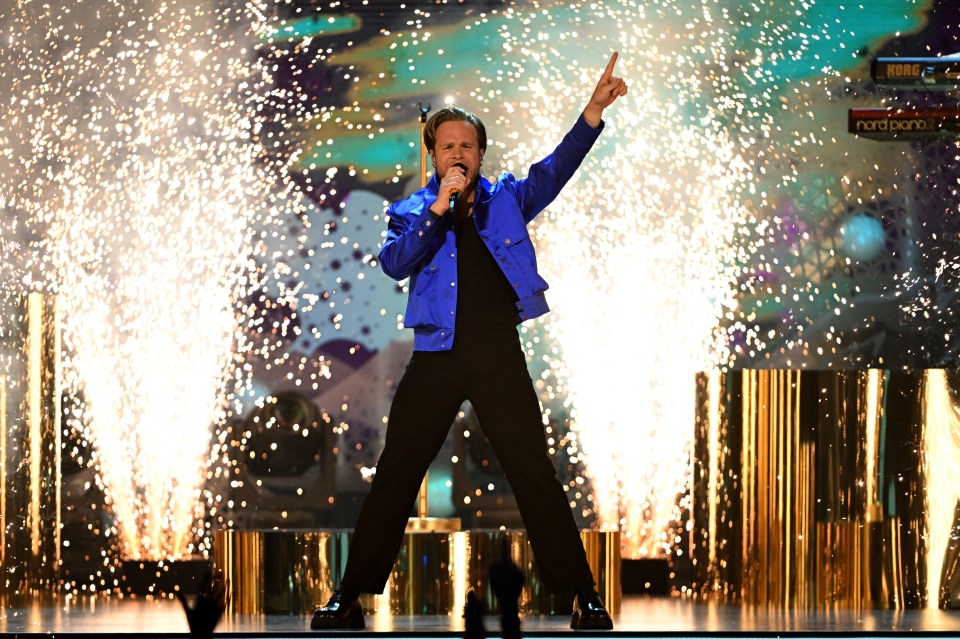 a man in a blue jacket singing into a microphone
