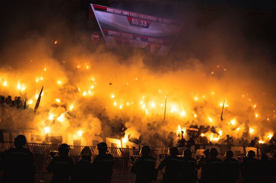a crowd of people with flares in front of a scoreboard that says 55:33