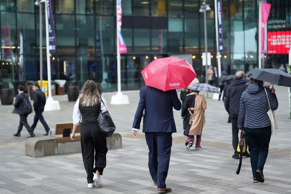 a man in a suit carrying a red umbrella that says ' famous ' on it