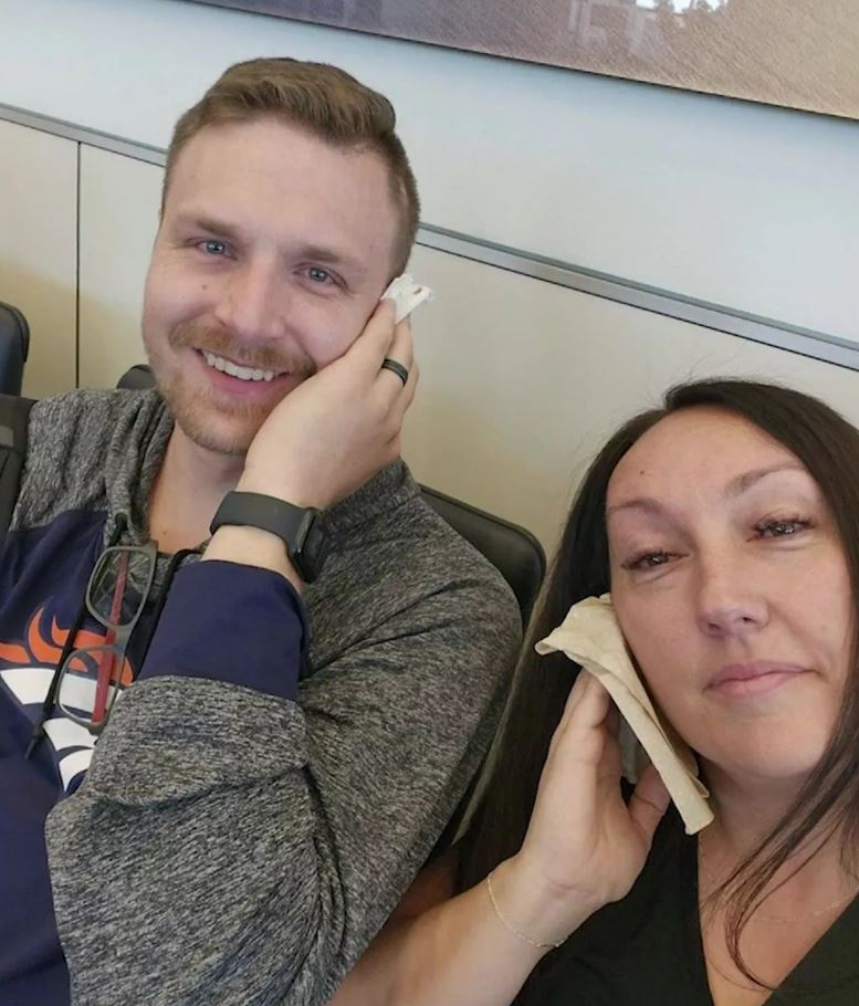 a man wearing a denver broncos shirt sits next to a woman