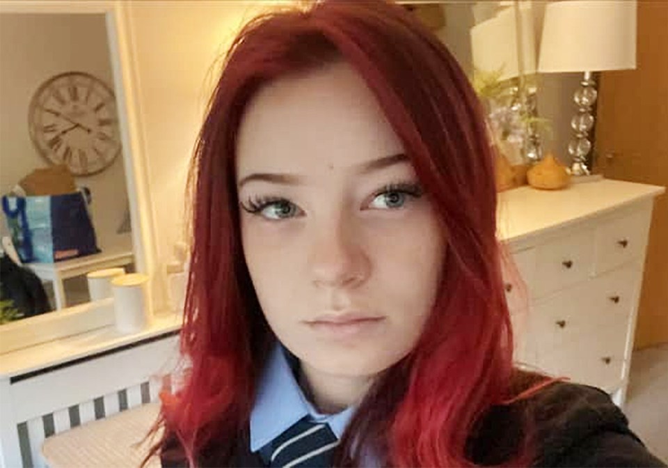 a girl with red hair is taking a selfie in front of a mirror .