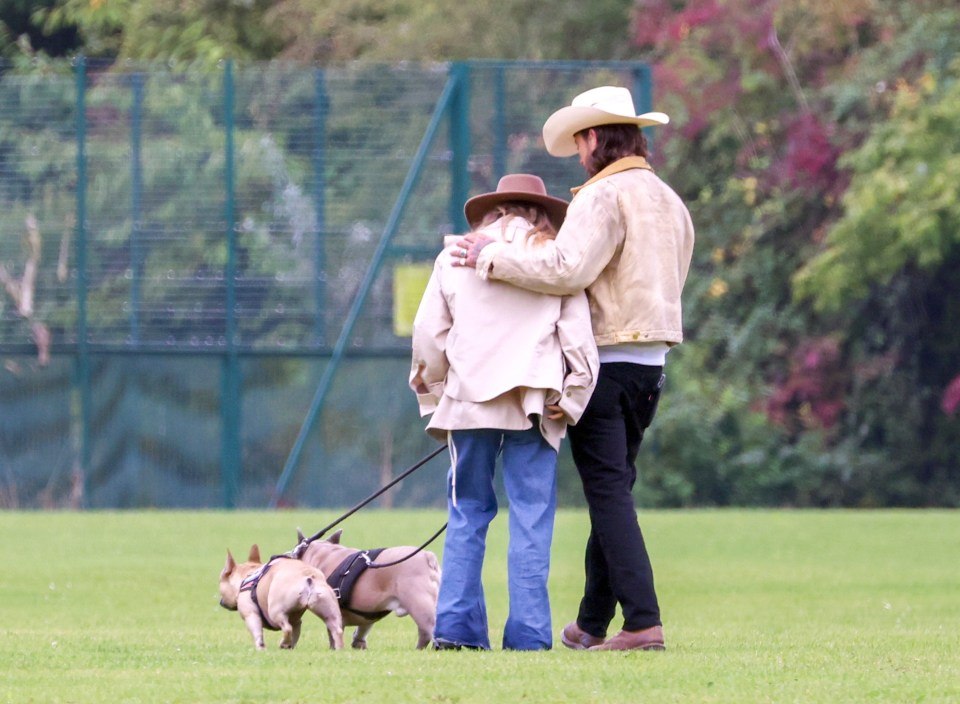 a man in a cowboy hat walks a woman and two dogs