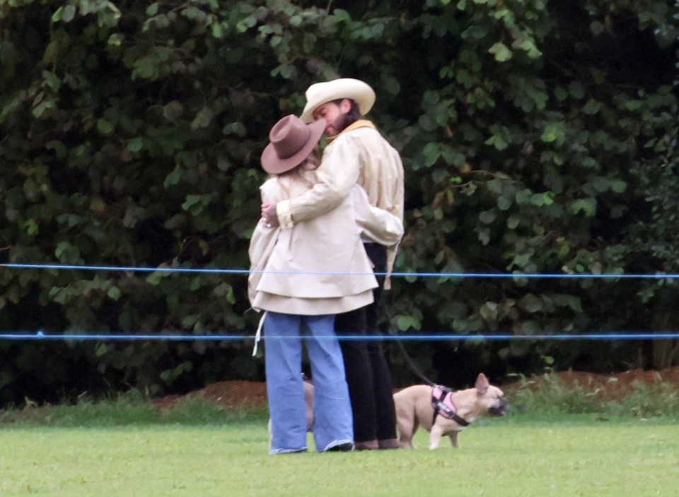 a man in a cowboy hat kisses a woman while a dog looks on