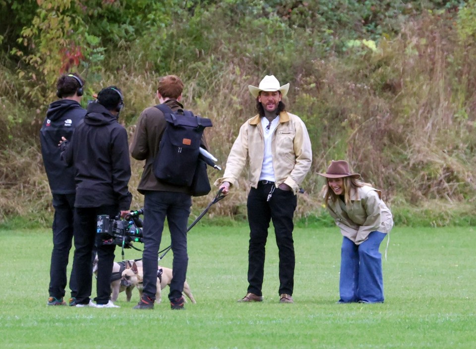 a man in a cowboy hat talks to a woman in a field