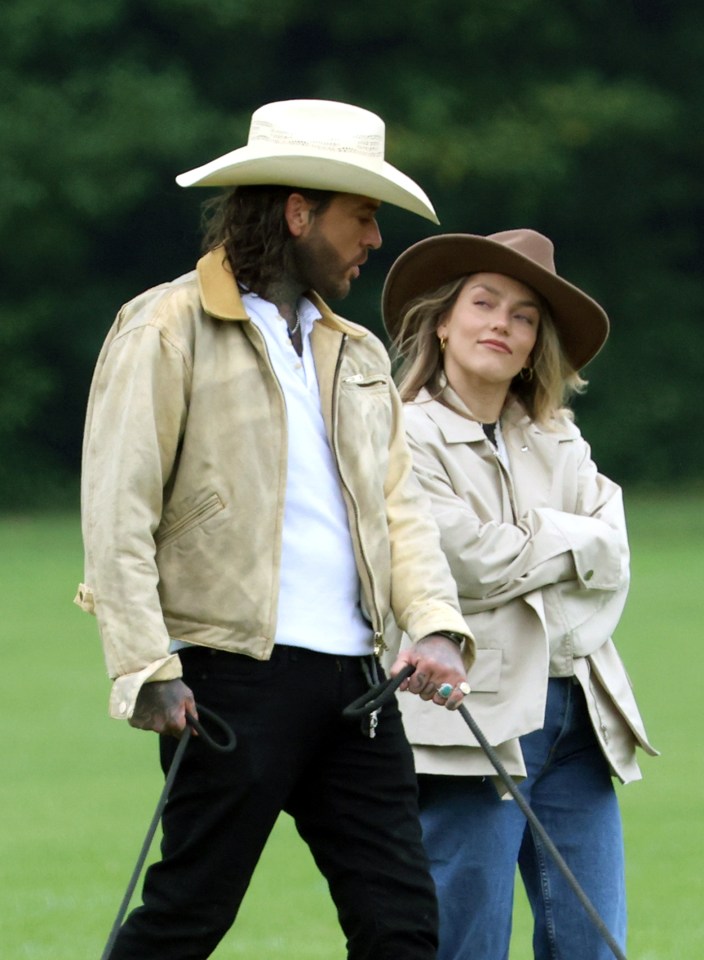 a man in a cowboy hat holds a leash next to a woman