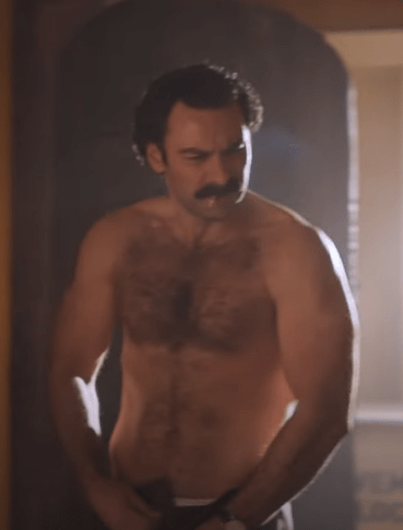 a shirtless man with a mustache is standing in a doorway