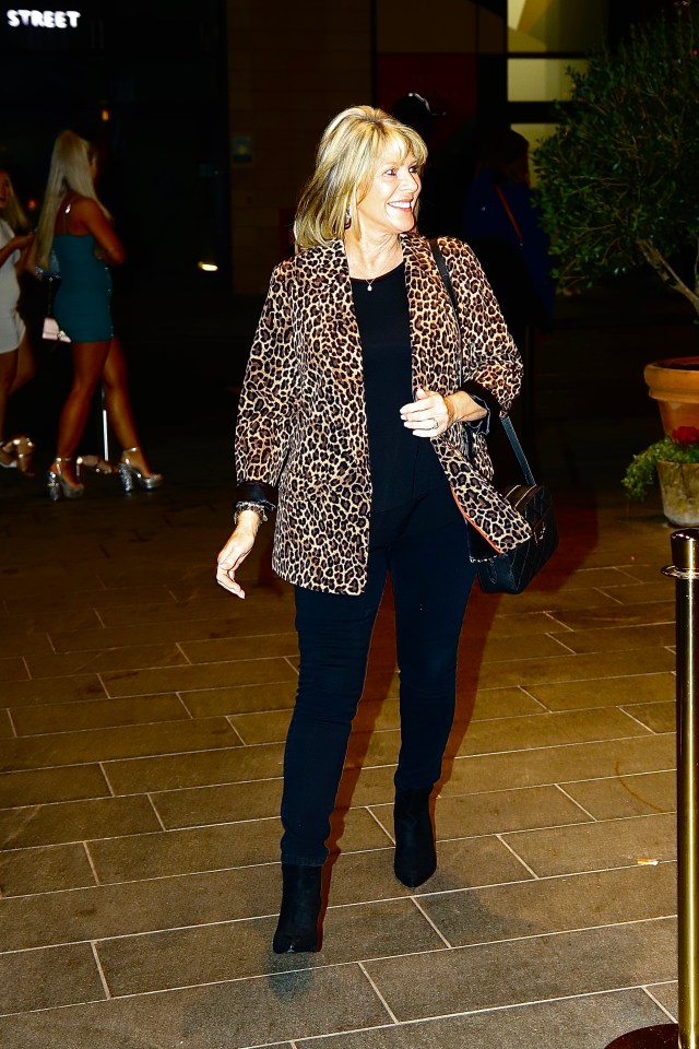 a woman wearing a leopard print jacket and black pants