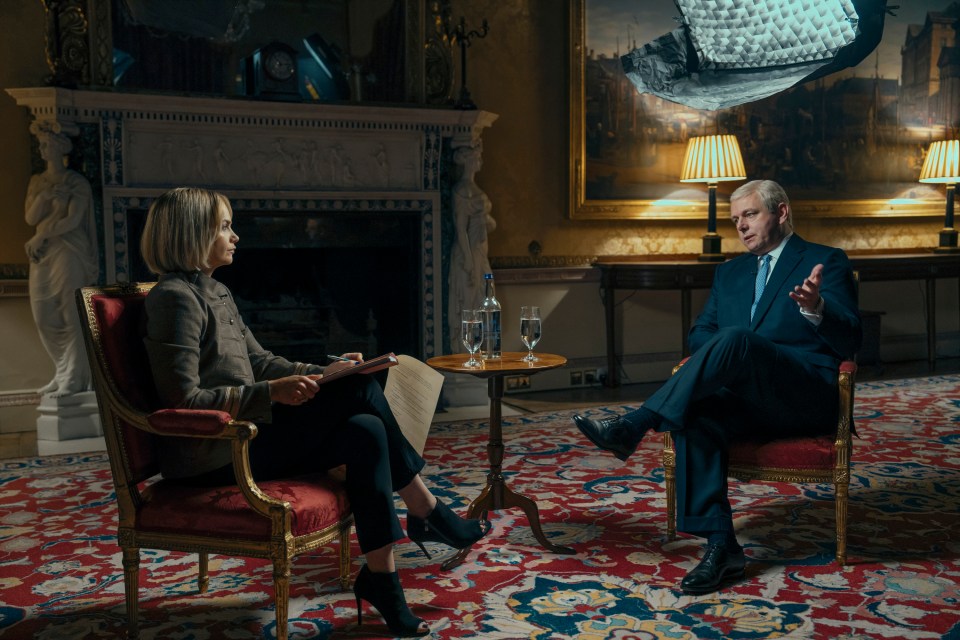a man in a suit sits next to a woman in a chair