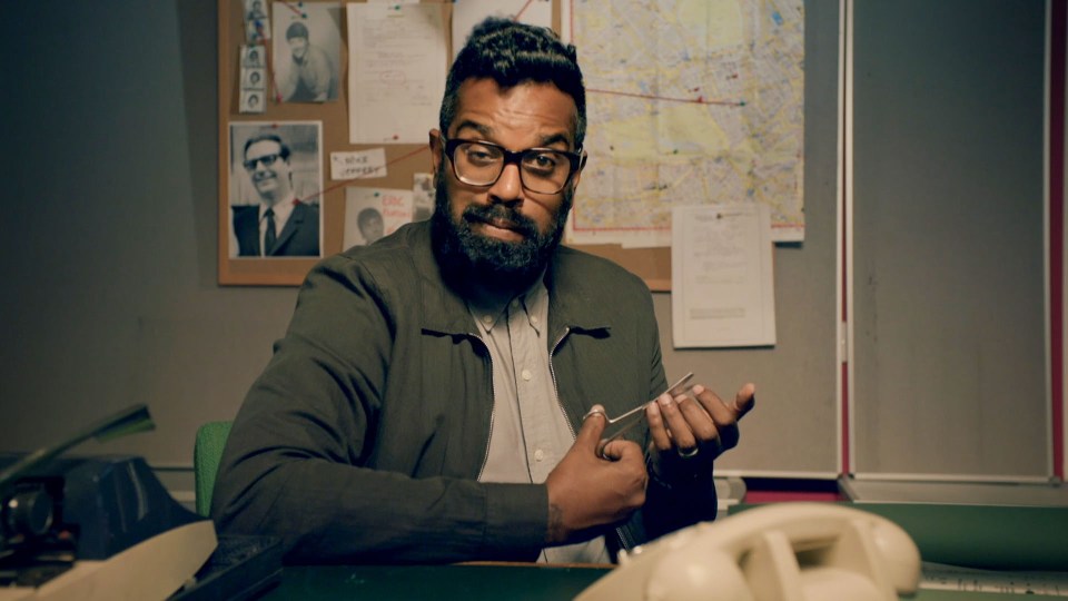 a man with glasses and a beard is sitting at a desk in front of a bulletin board that says " what changed "