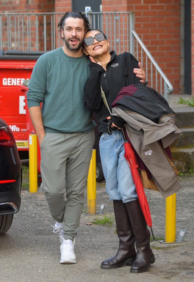 a man and woman are posing for a picture in front of a red dumpster that says gener