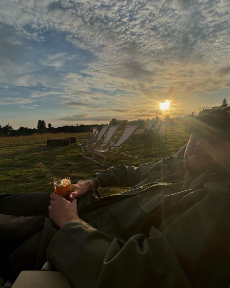 a man sitting in a field with a drink in his hand