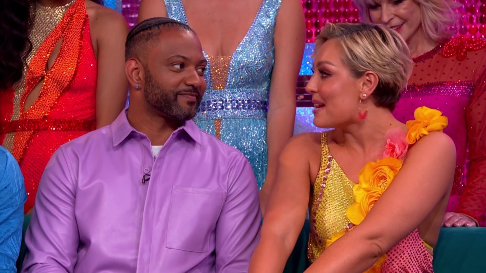 a man in a purple shirt sits next to a woman in a colorful dress