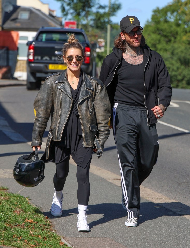 a man wearing a black hat with the letter p on it walks with a woman