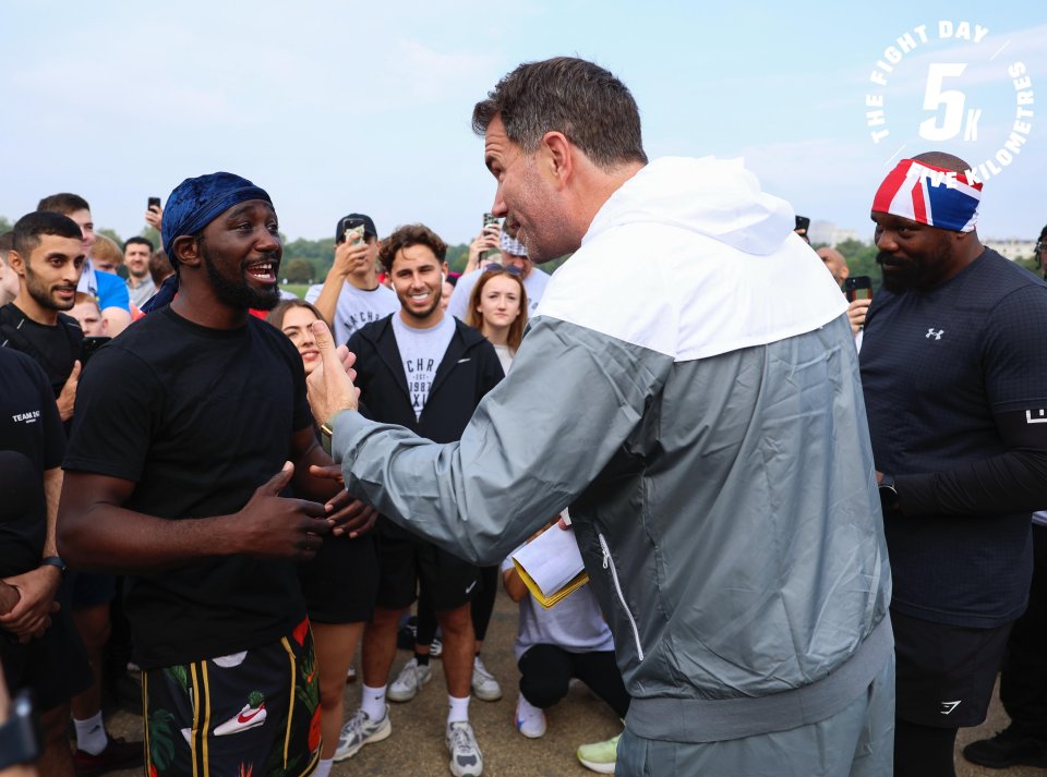 a man shakes hands with another man in front of a sign that says the fight day 5k