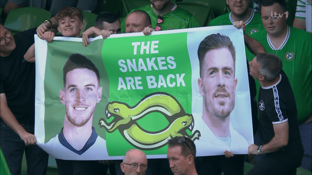 a group of people holding a sign that says the snakes are back
