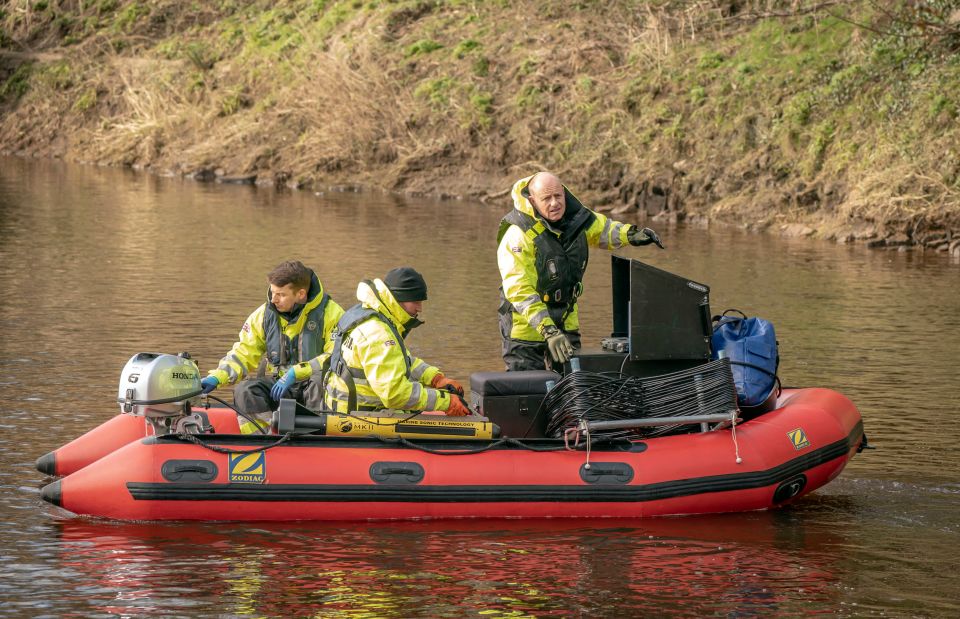three men are in a red zodiac boat with a yellow zodiac logo on the side