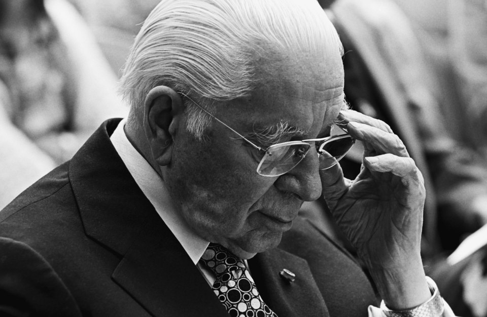 a man in a suit and tie adjusts his glasses