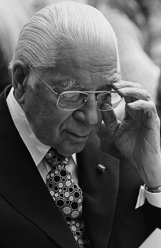 a man in a suit and tie adjusts his glasses