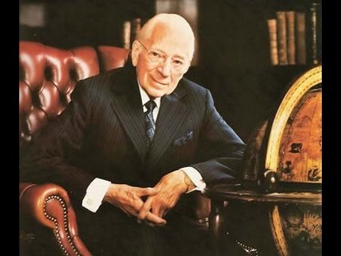 a man in a suit and tie is sitting in a chair next to a globe .