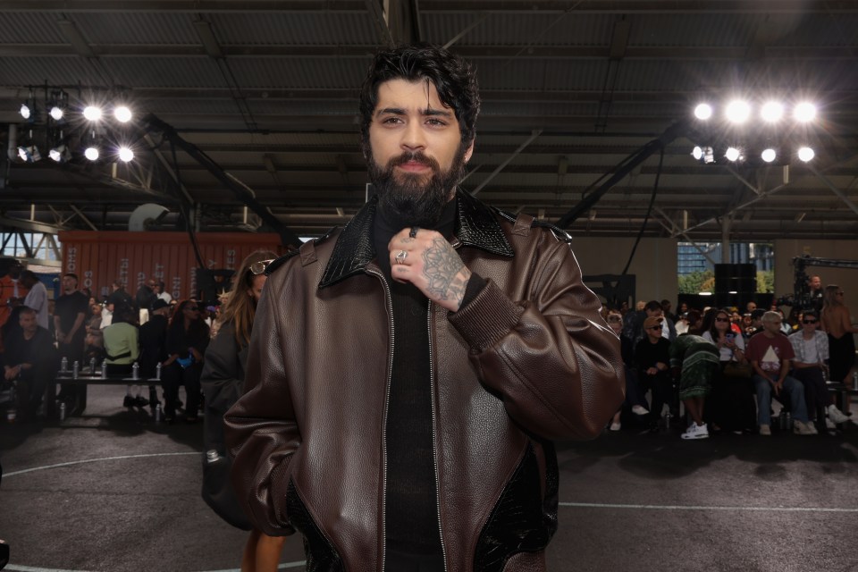 a man with a beard wears a brown leather jacket