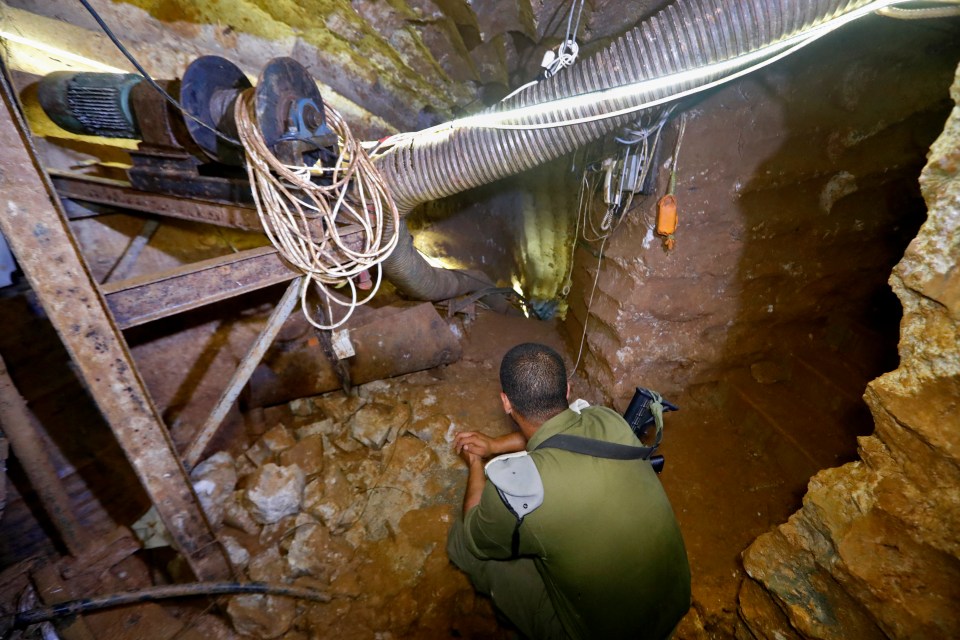 a man in a green uniform is kneeling down in a cave