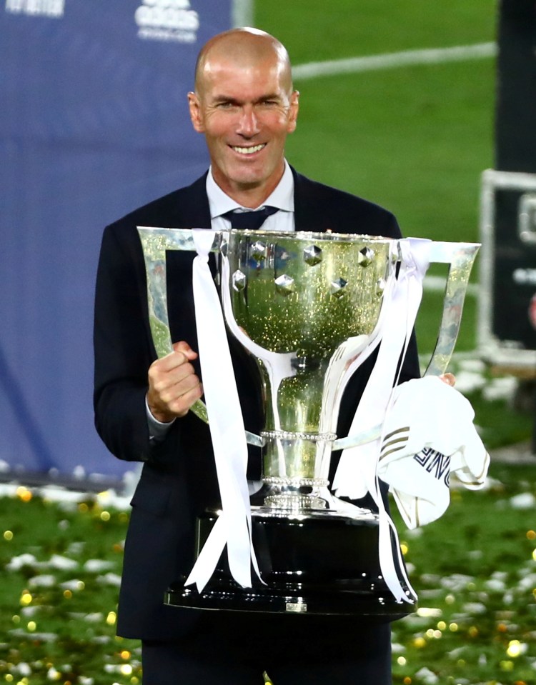 a man in a suit holds a trophy with the letter v on it