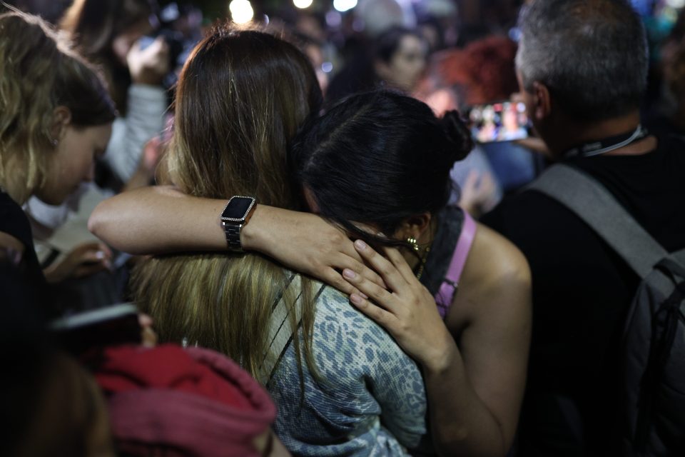 a woman wearing an apple watch is hugging another woman