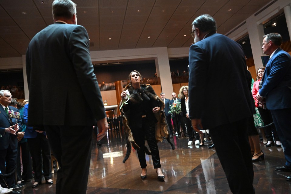 a woman in a fur coat stands in a crowd of people
