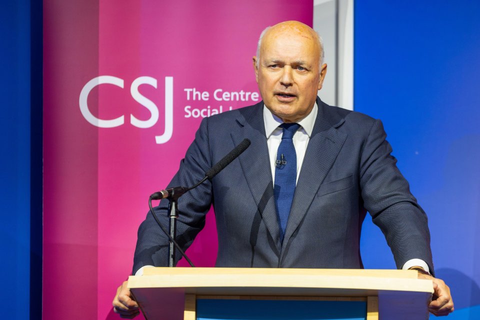 a man stands at a podium in front of a csj banner