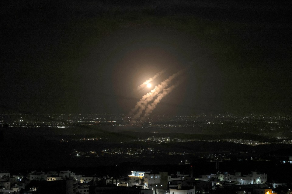 a rocket flies through the night sky over a city