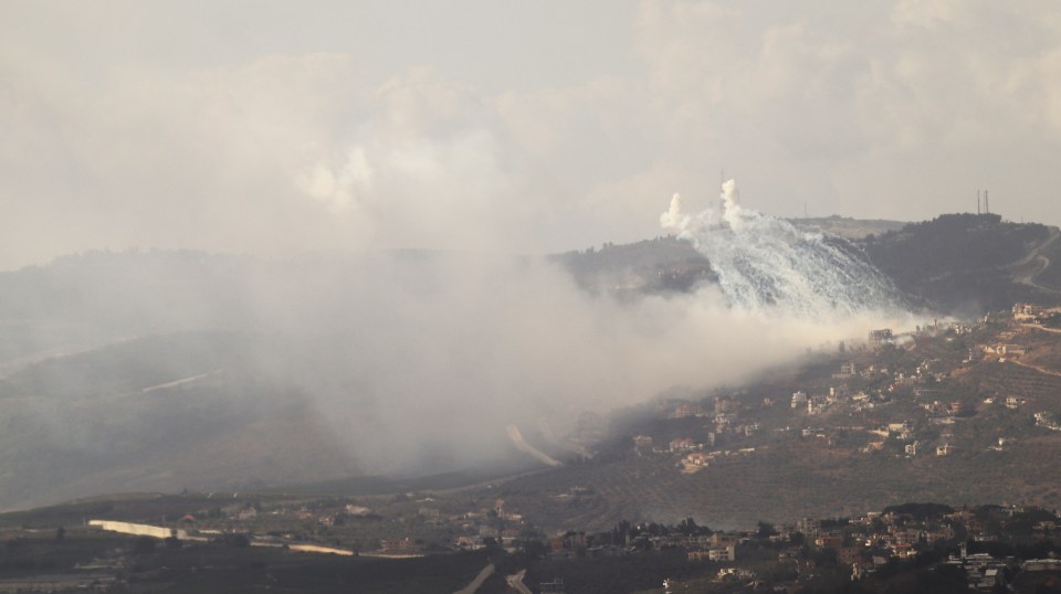 a mountain with smoke coming out of it and houses in the background