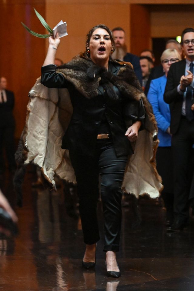 a woman in a fur coat holds up a piece of paper