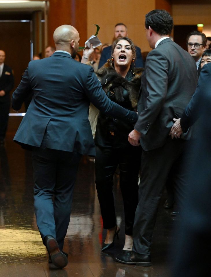 a woman in a fur coat is being held by two men in suits