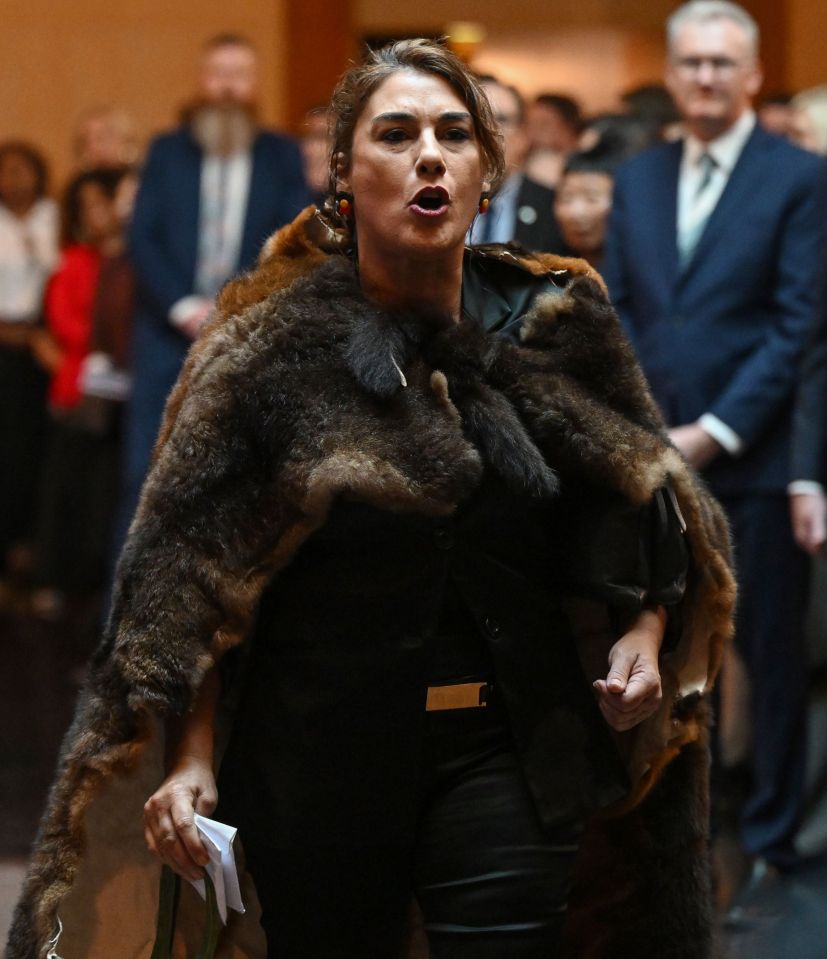 a woman in a fur coat stands in front of a crowd
