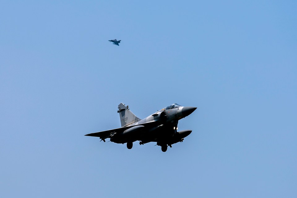 two fighter jets are flying in the sky and one of them has a sticker on the side that says ' a '