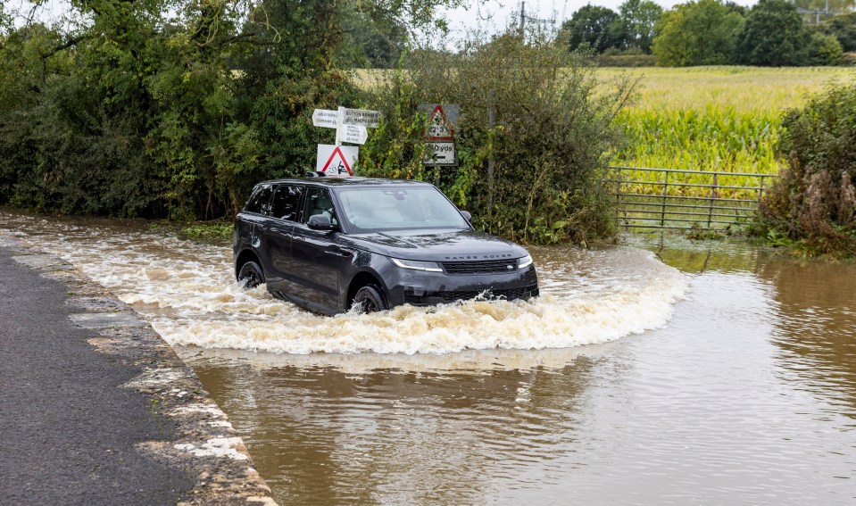 a range rover is driving through a flooded road