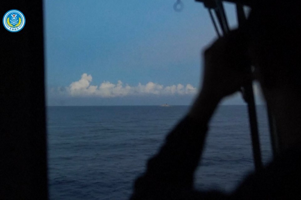 a person looking out a window at the ocean with a logo for the chinese navy