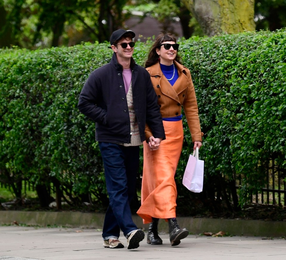a man and woman are walking down a sidewalk holding hands