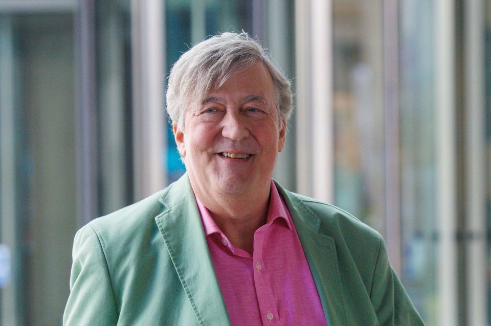 a man wearing a green jacket and a pink shirt smiles for the camera