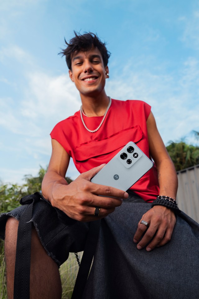 a man in a red shirt is holding a motorola phone
