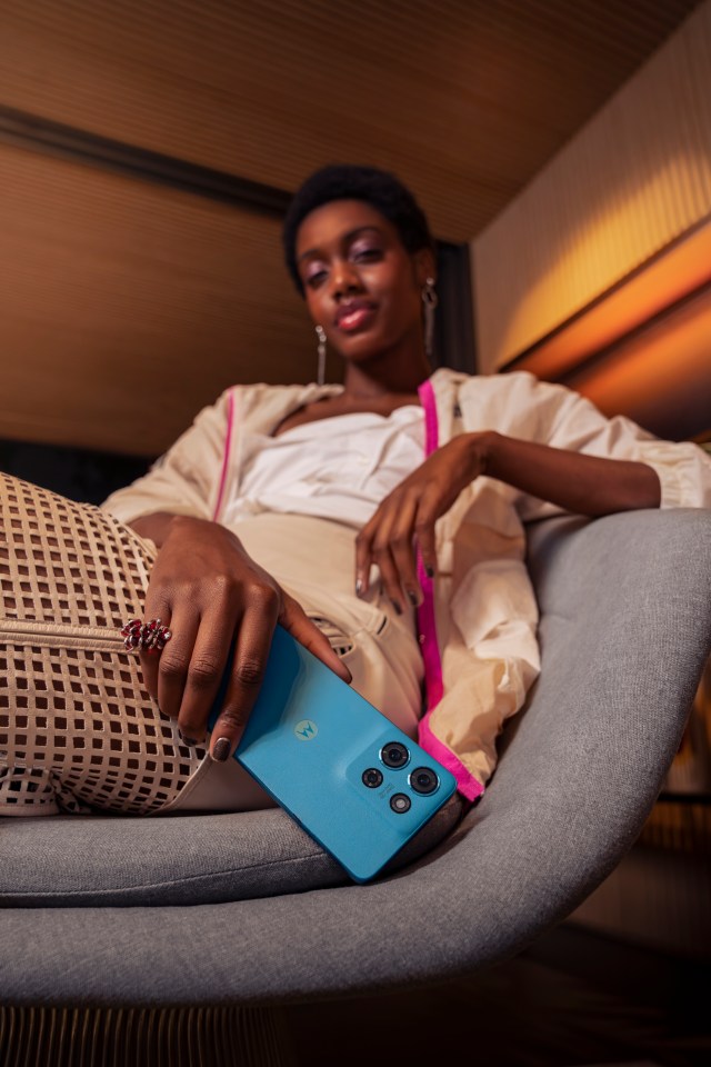 a woman laying on a couch holding a blue motorola phone