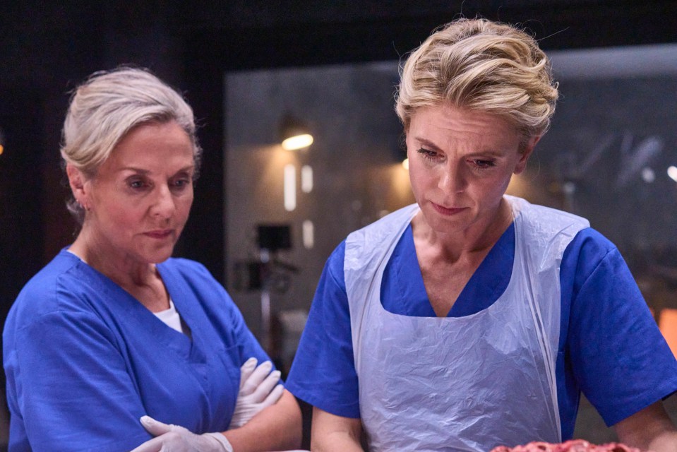 two women in blue scrubs are looking at a piece of meat
