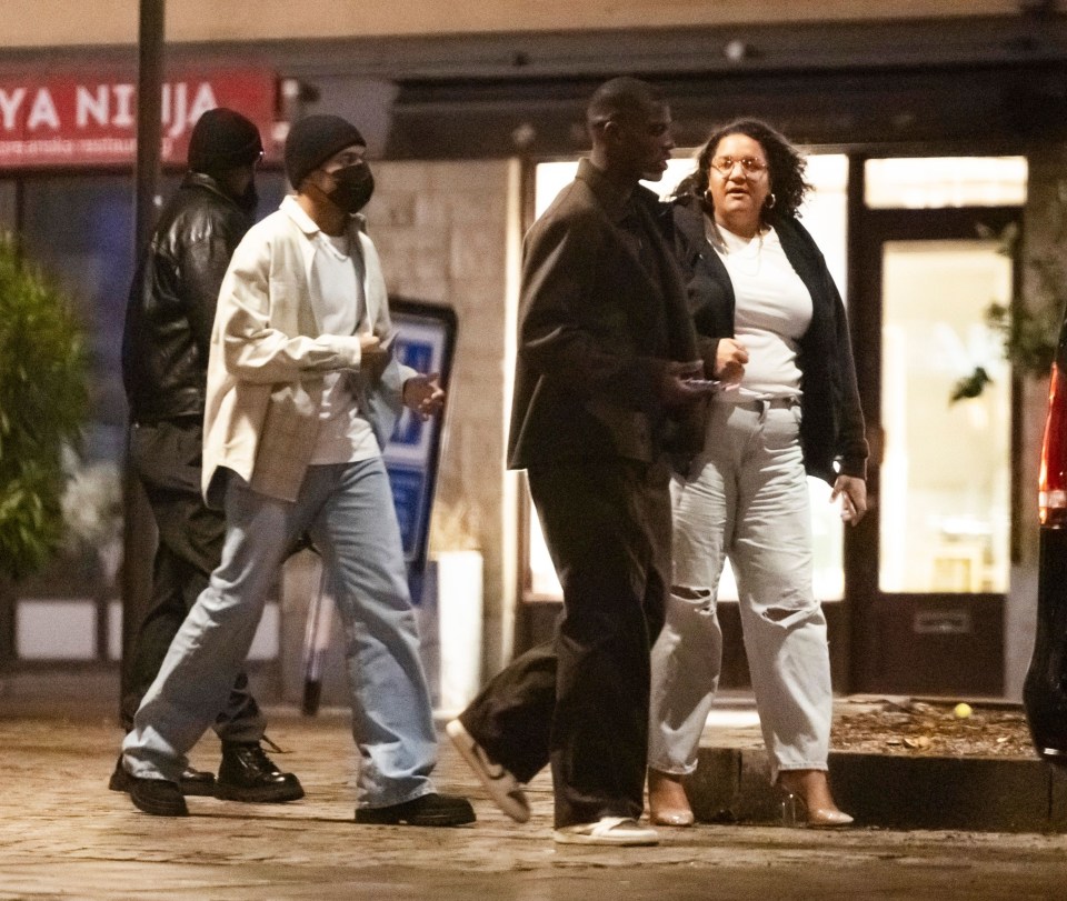 a group of people walking down a street in front of izakaya