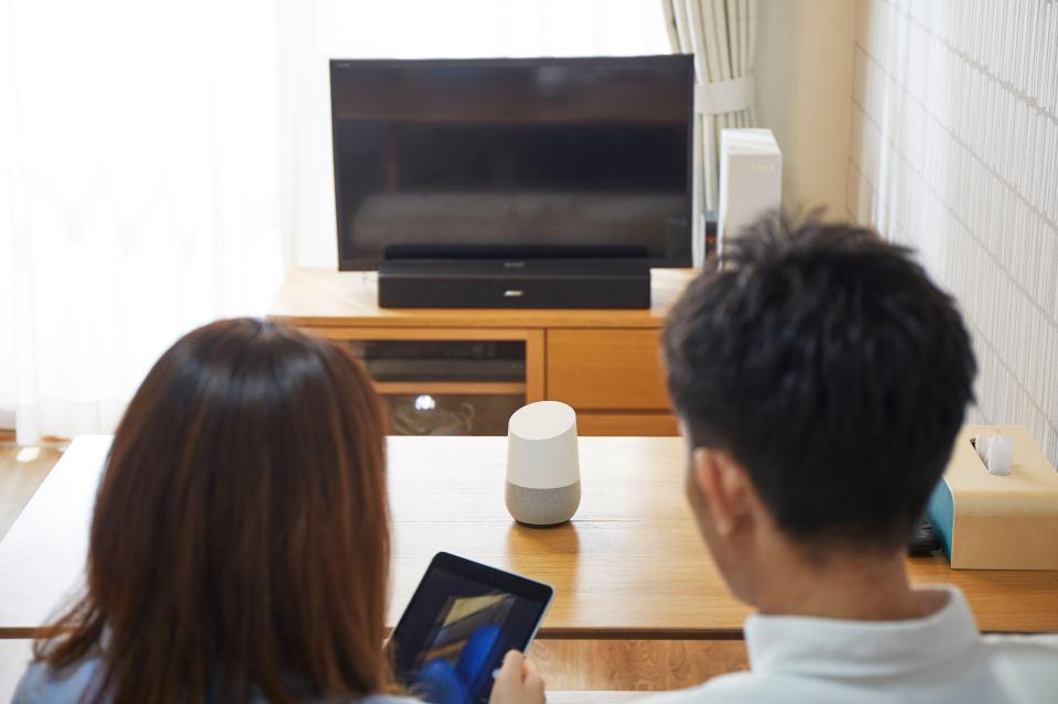 a man and a woman sit at a table looking at a television