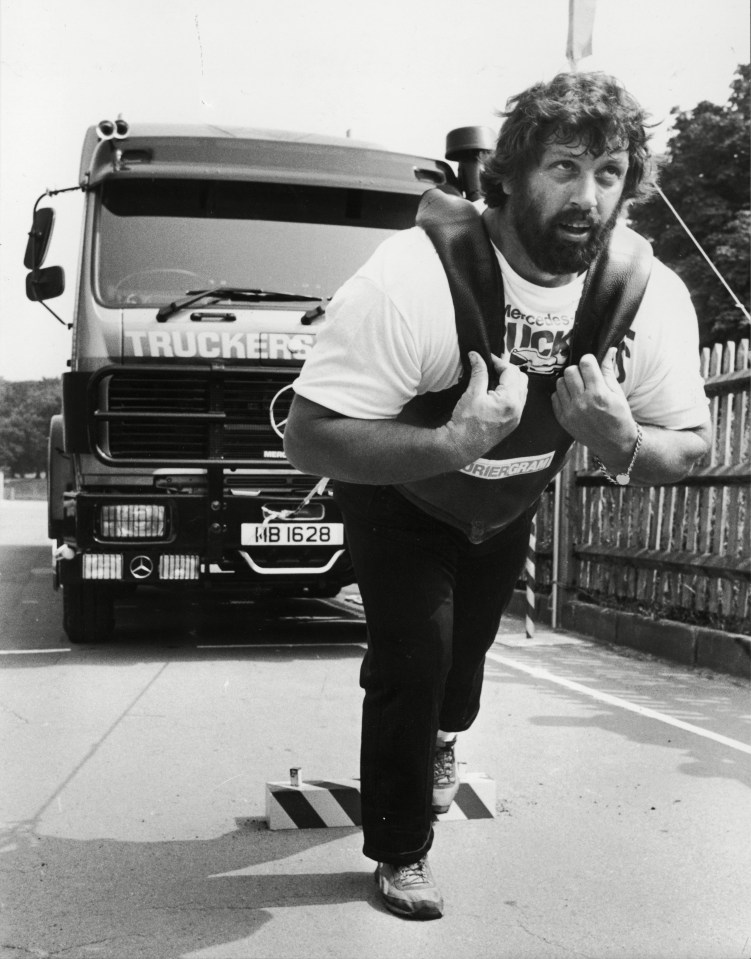 a man is carrying a weight in front of a truck that says truckers